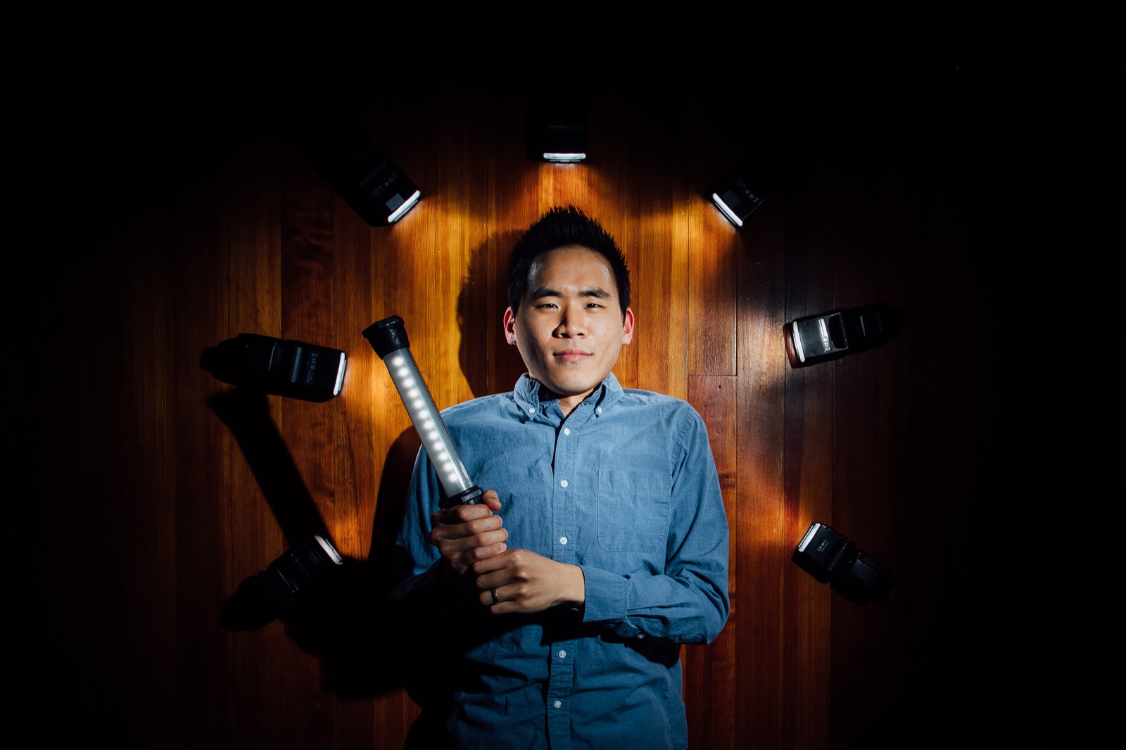 Portrait of Aiden surrounded by off-camera flashes and holding a handheld light