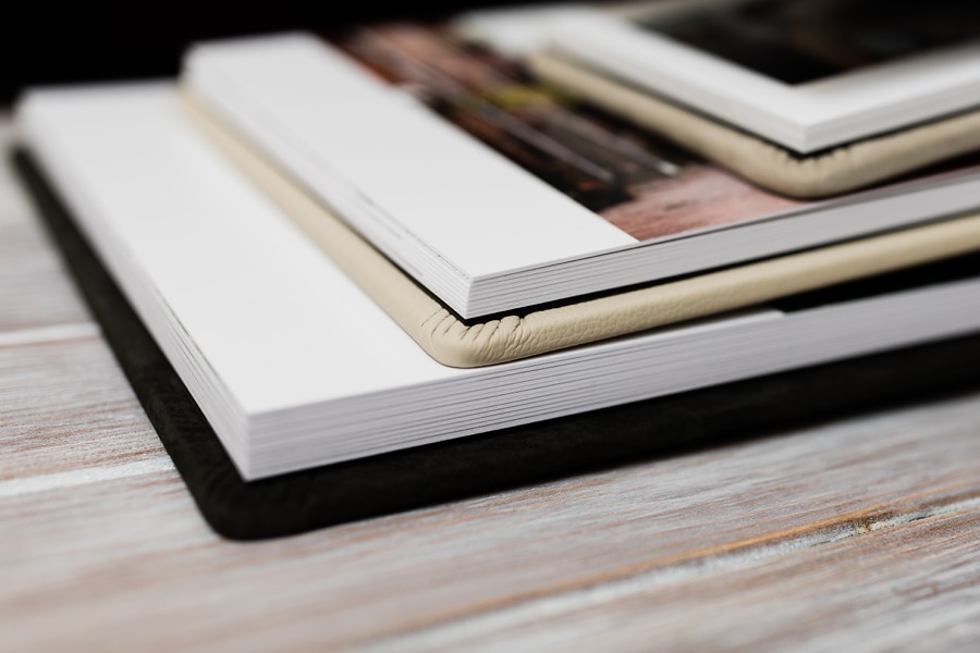 Handcrafted wedding albums stacked open to show their substantial lay-flat pages