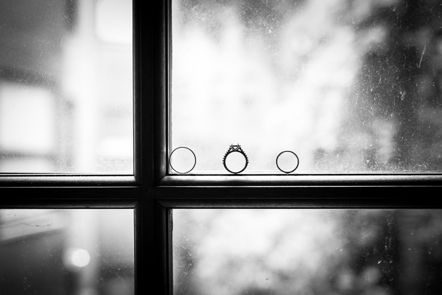 Creative black and white of wedding rings on rustic window Massachusetts.