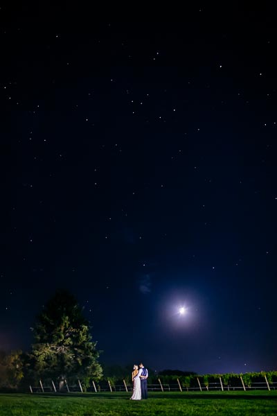 A couple stands beneath a star-filled night sky